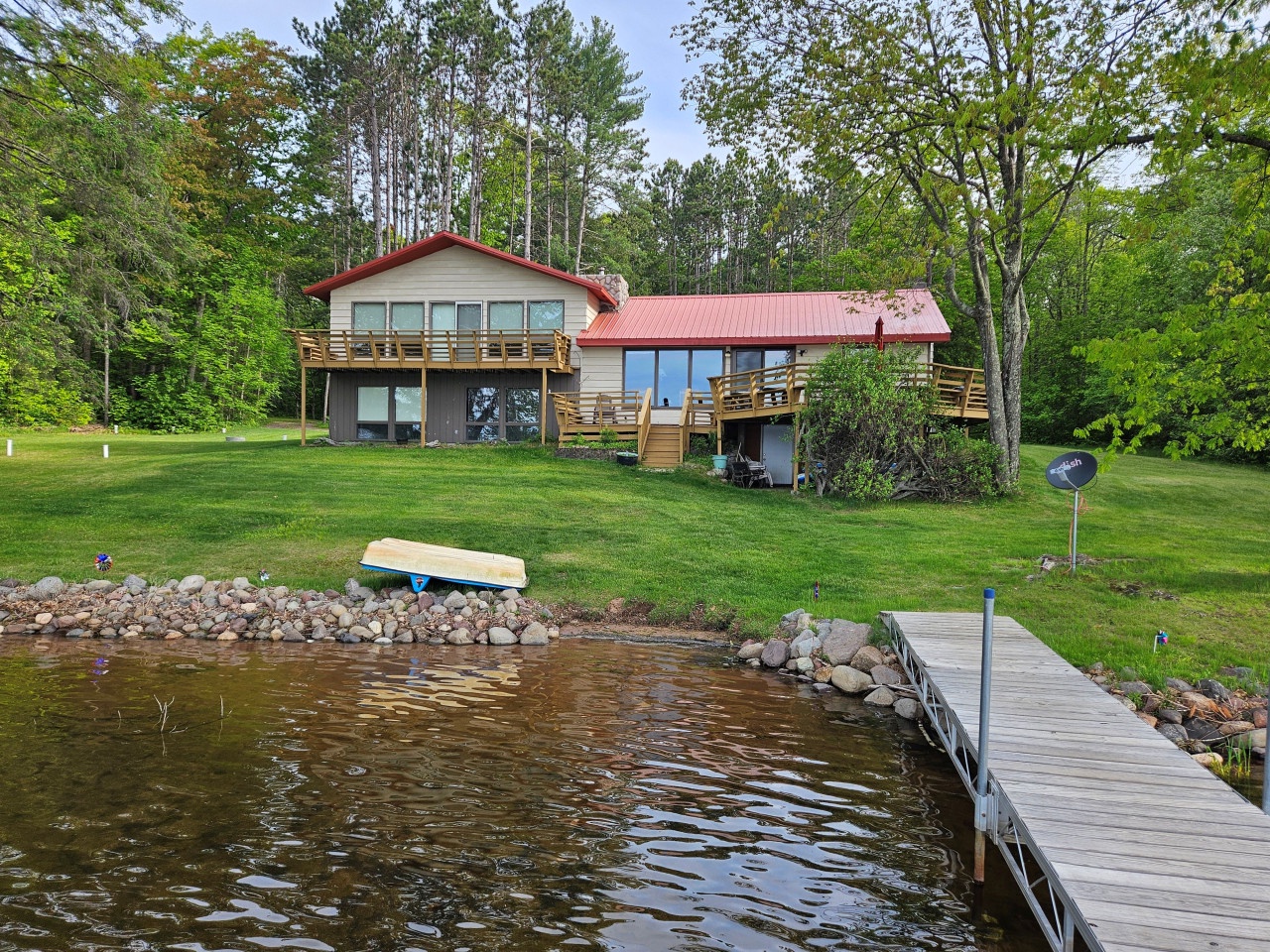 Waterfront retreat with private dock on pristine lake, surrounded by lush forest and spacious grounds for ultimate relaxation.
