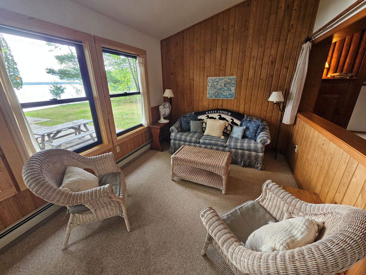 Sink into cozy wicker chairs and plaid sofa while enjoying serene lake views through your panoramic windows.