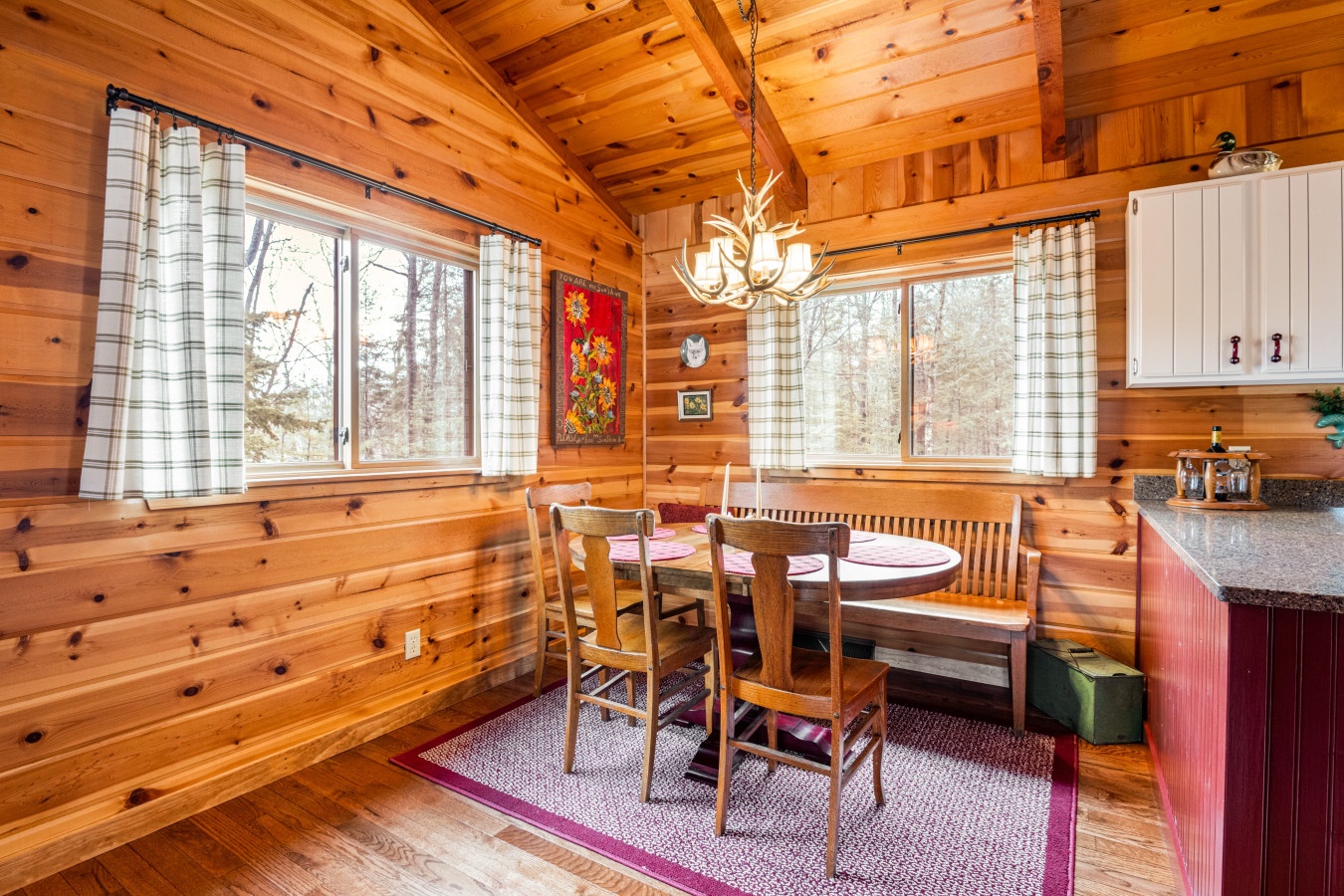 Gather around this rustic dining nook where warm wood surrounds you and forest views create the perfect cabin atmosphere.