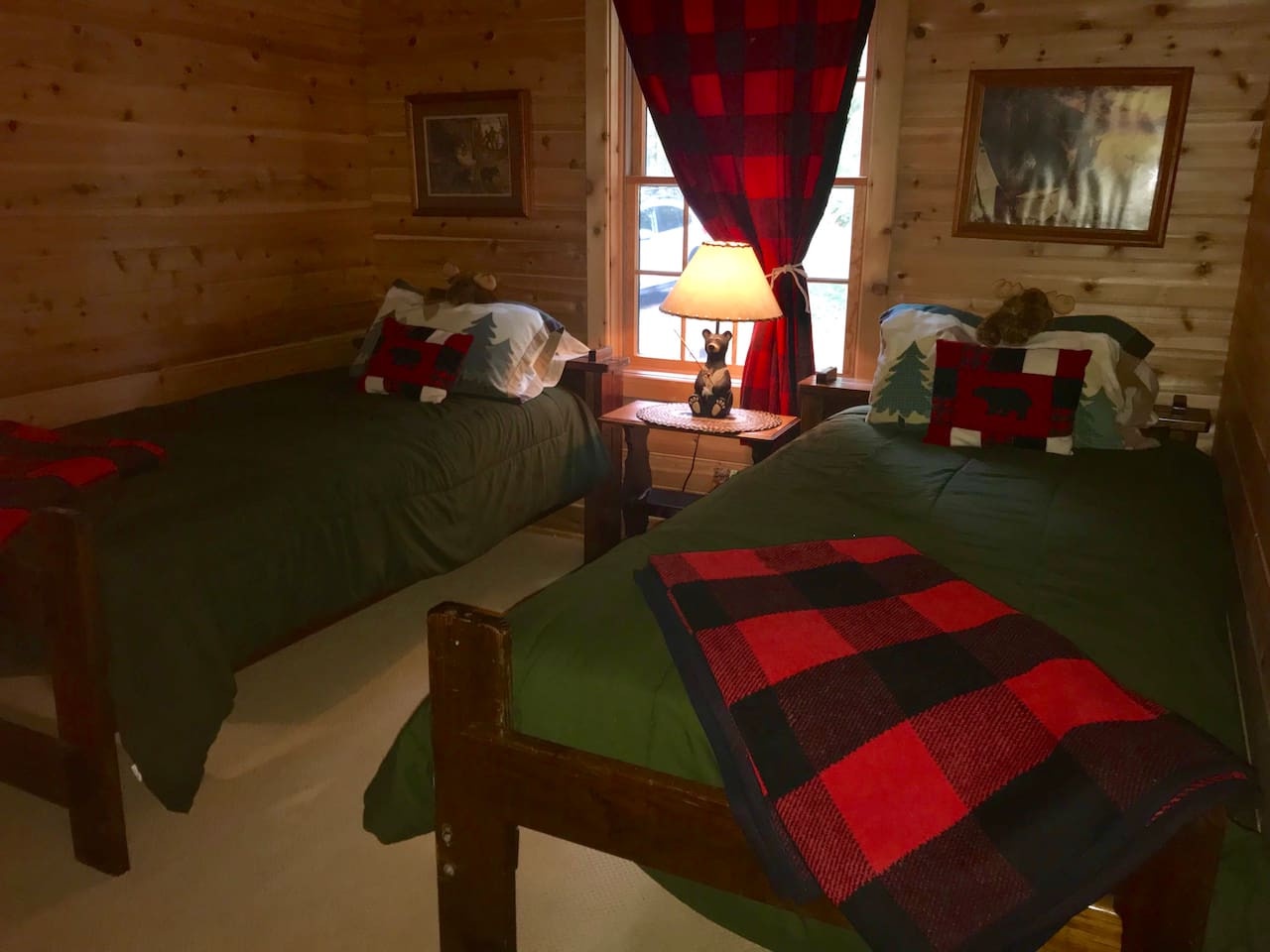 Cozy up in your rustic twin bedroom with charming plaid accents and warm wood walls that create the perfect mountain retreat atmosphere.
