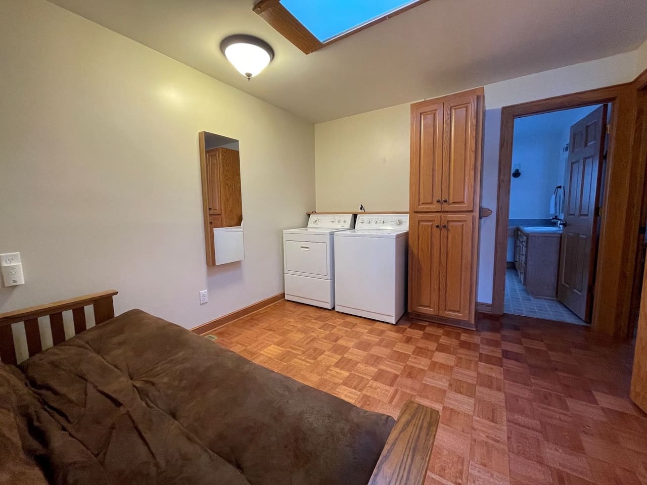 Your laundry routine becomes effortless in this thoughtfully designed space, featuring full-size washer and dryer with natural light streaming through the skylight overhead.
