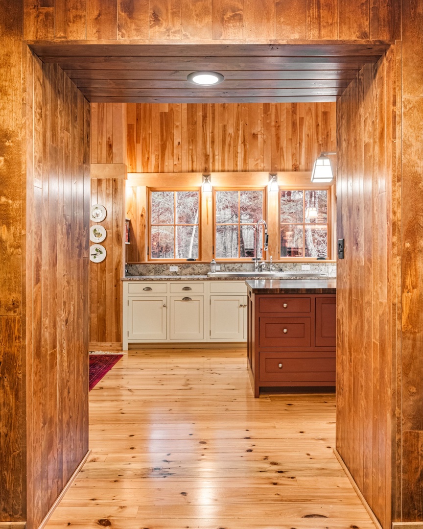 Step into your rustic kitchen where warm wood surrounds you and granite counters invite culinary adventures with forest views.