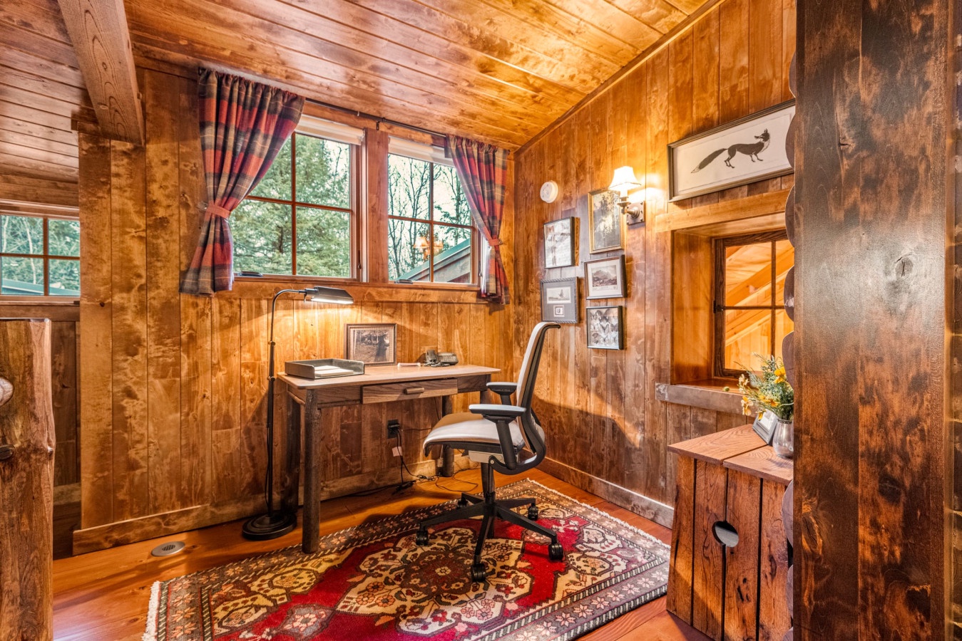 Work from your cozy cabin office with warm wood walls, natural light, and rustic charm creating the perfect peaceful workspace.