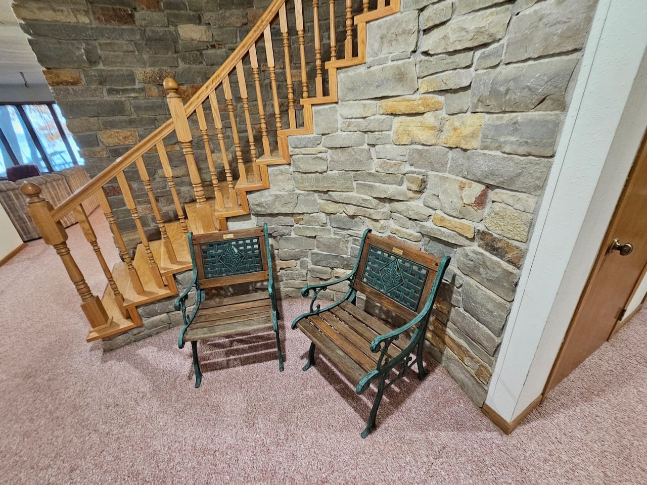 Settle into charming vintage chairs beneath the rustic stone staircase - your perfect reading nook awaits.