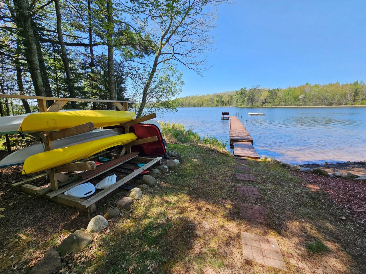 Kayaks and canoes await your lake adventures, with a private dock stretching into crystal-clear waters surrounded by peaceful forest.
