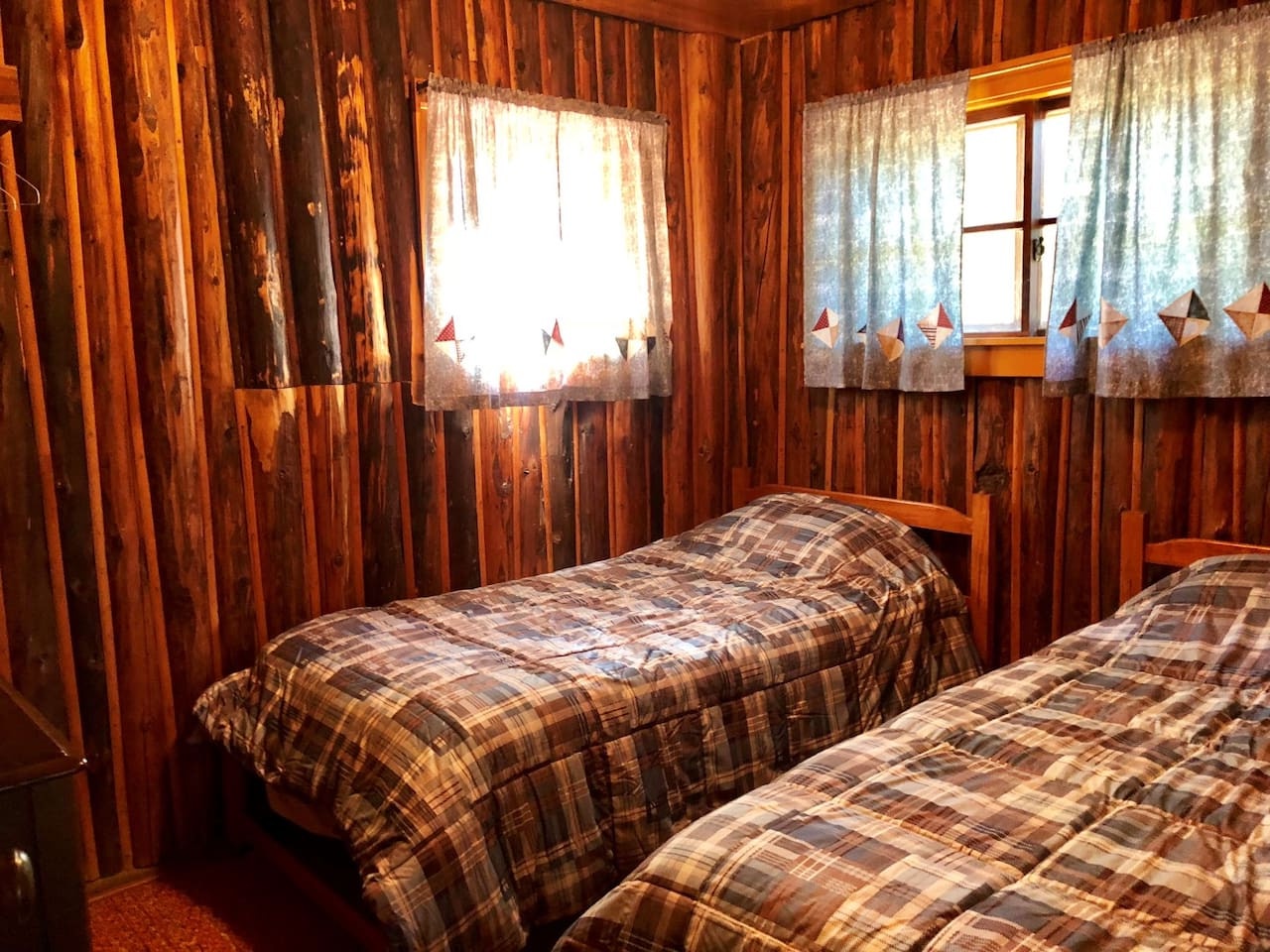 Cozy twin beds with warm plaid bedding invite restful nights in this charming wood-paneled bedroom.