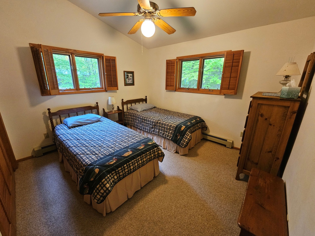 Your cozy twin bedroom features rustic charm with wooden shutters framing garden views, perfect for restful nights.