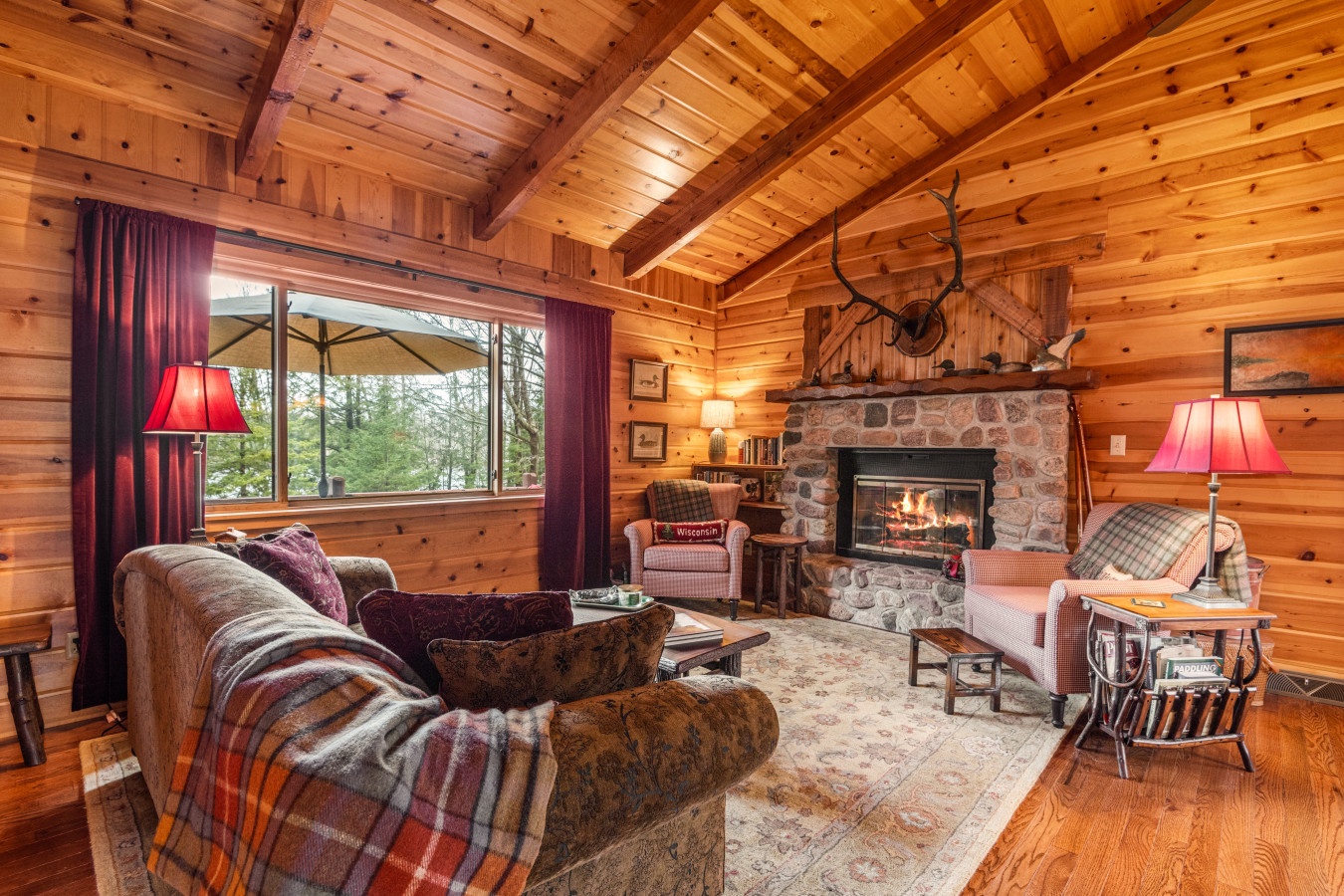 Cozy up by the crackling fireplace in this rustic living room where warm wood surrounds you and plaid furnishings invite relaxation.
