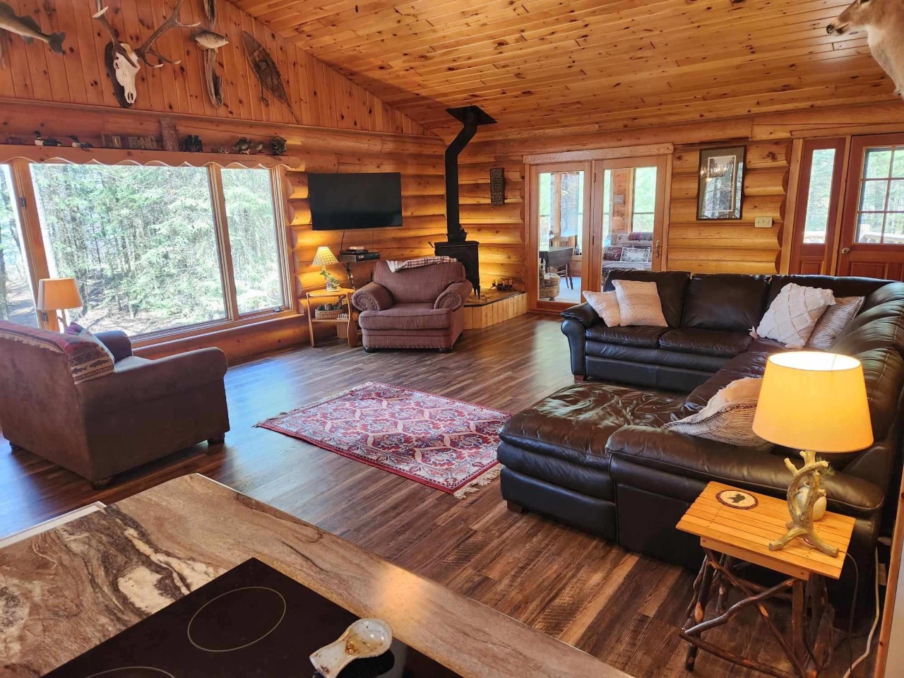 Sink into luxurious leather seating beside the stone fireplace, where warm wood surrounds you and forest views create your perfect retreat.