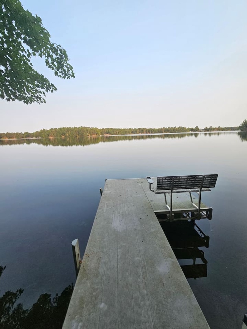 Tranquil lakefront setting with private dock and seating area surrounded by natural forest landscape.