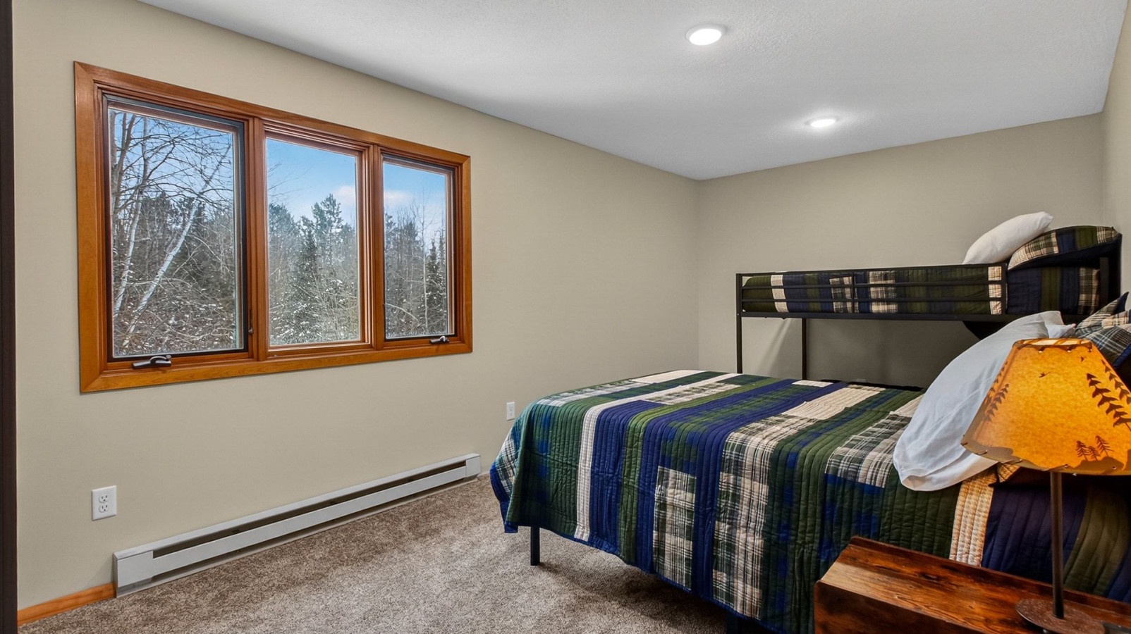 Wake up to beautiful winter forest views from your cozy bedroom featuring comfortable bunk beds perfect for family stays.