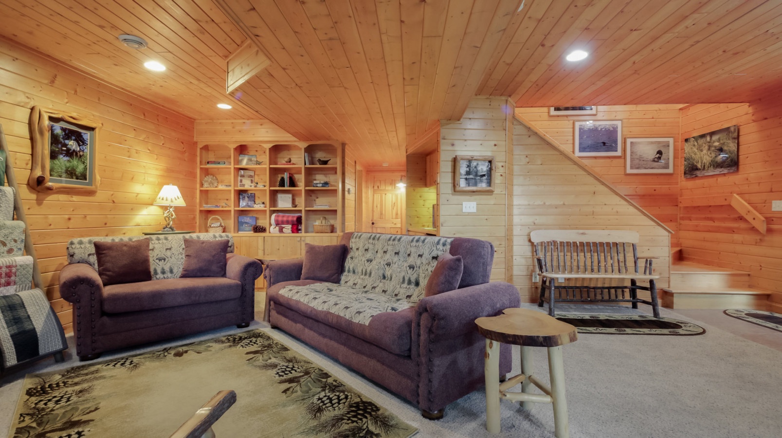 Sink into plush sofas surrounded by warm wood walls and rustic charm. Your cozy retreat features built-in shelving and comfortable seating.