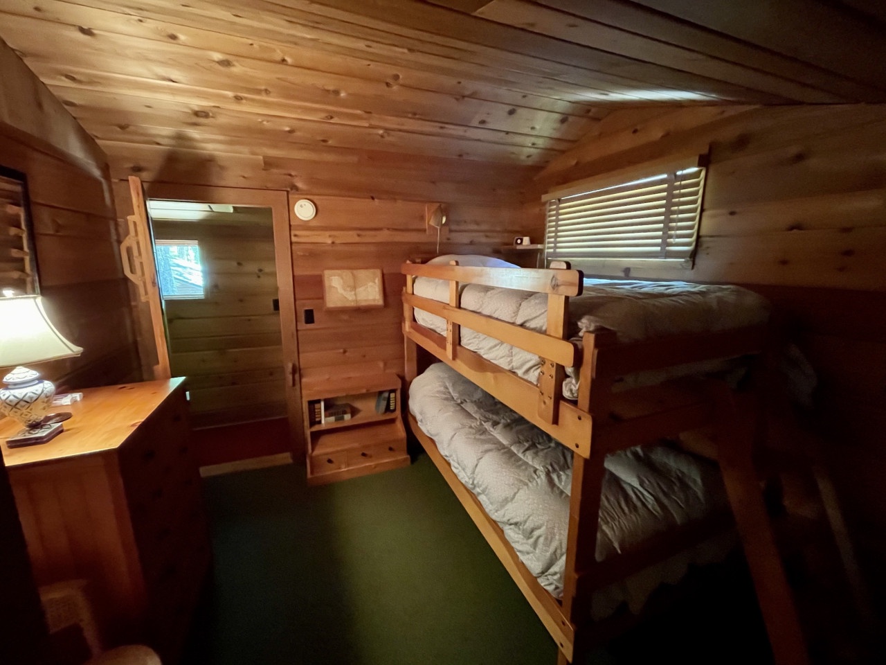 Your cozy cabin bedroom features warm wood paneling and comfortable bunk beds, perfect for family adventures in this rustic retreat.