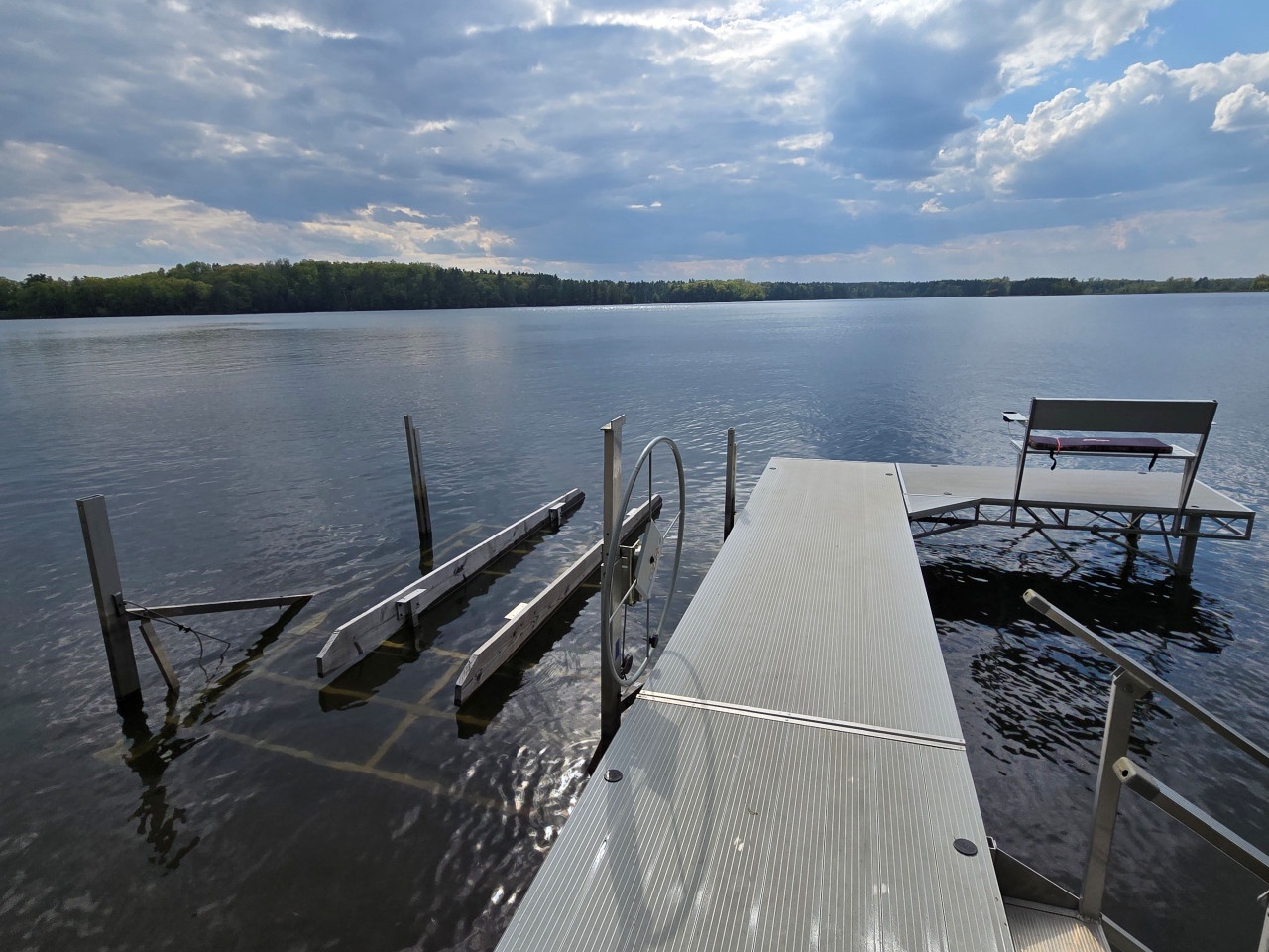Private dock extends into pristine lake waters, offering boat access and serene waterfront relaxation beneath dramatic skies.