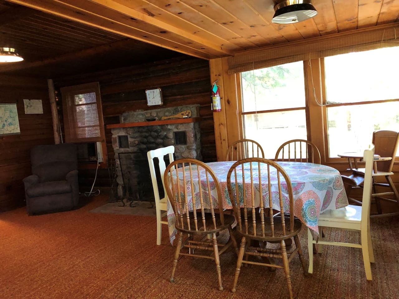 Gather around your cozy dining table where rustic wood beams and stone fireplace create the perfect cabin atmosphere for memorable meals together.