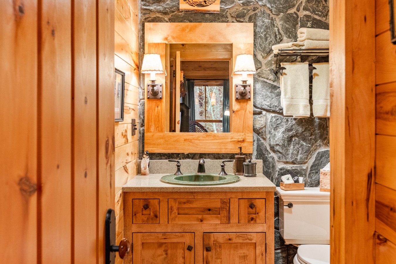 Unwind in your rustic bathroom featuring warm wood vanity, elegant stone accents, and thoughtful amenities for a peaceful retreat.