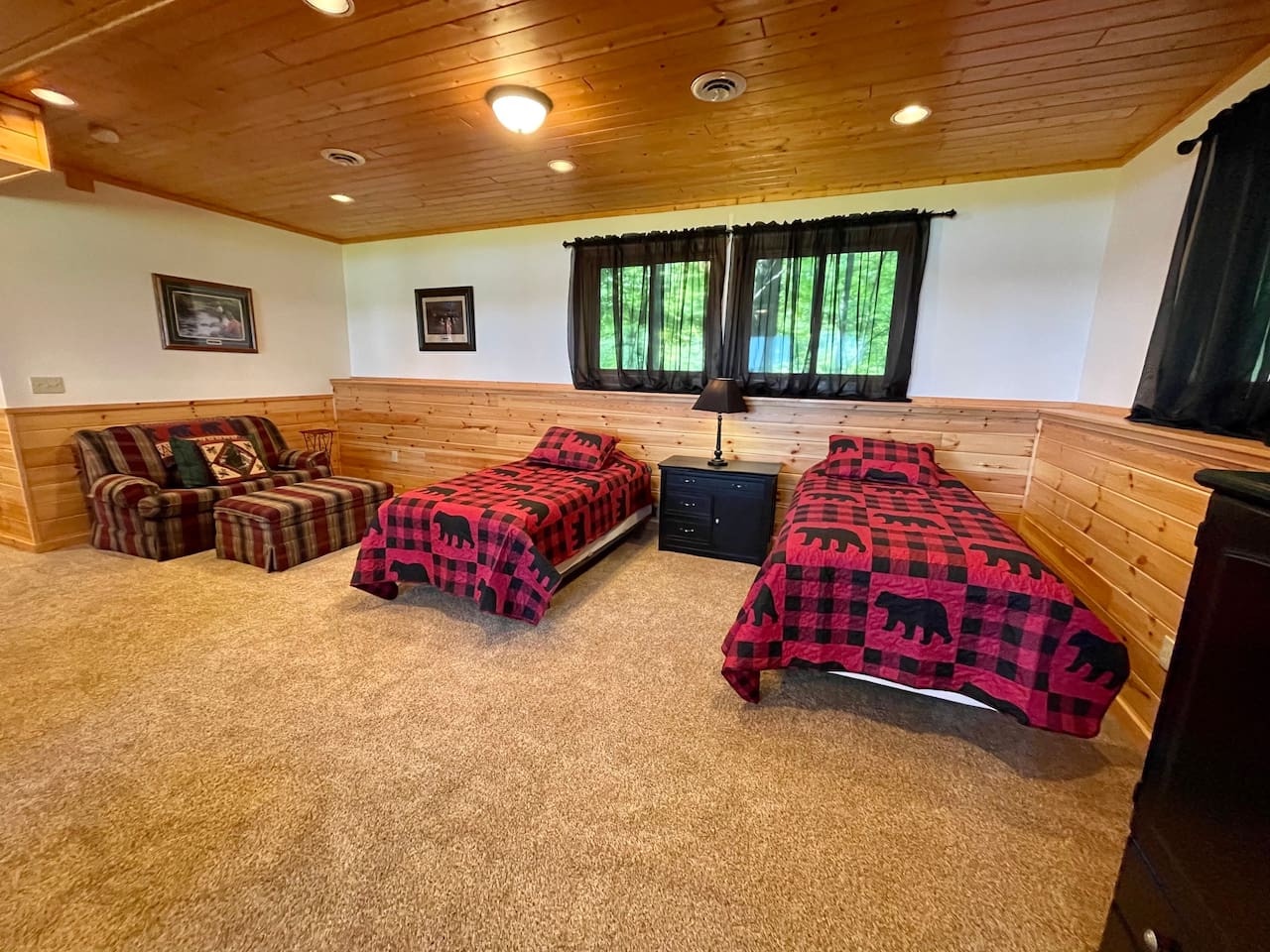 Cozy cabin bedroom with rustic charm awaits your group - twin beds with buffalo plaid comforters and comfy seating create your perfect mountain retreat.