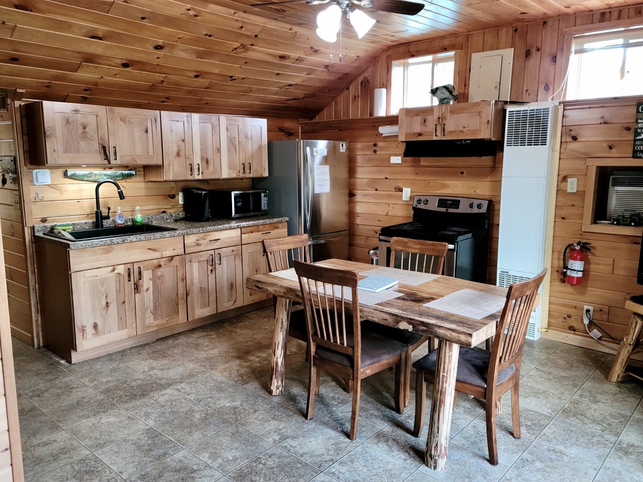 Your rustic cabin kitchen combines modern convenience with cozy charm, featuring granite counters, full appliances, and a handcrafted dining table perfect for family meals.