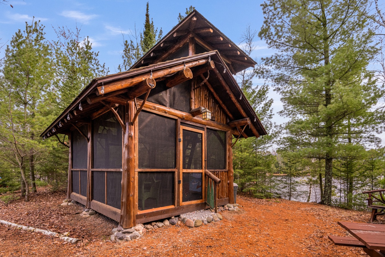 Rustic lakeside cabin surrounded by forest, offering peaceful retreat with screened porch and natural woodland setting.