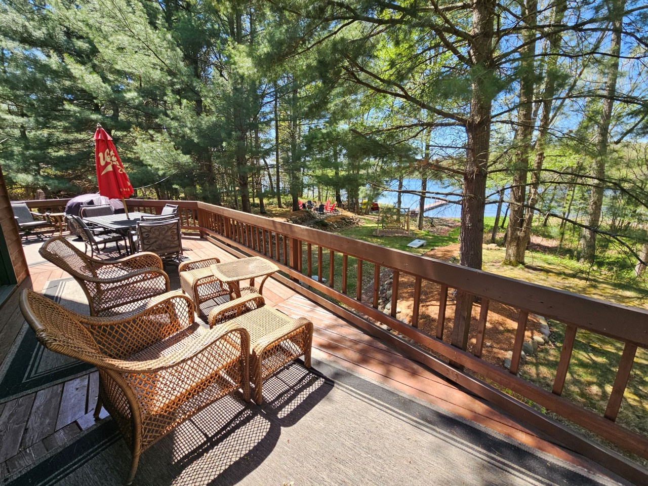 Unwind on your private deck with wicker seating overlooking tranquil lake views through towering pines—your perfect retreat awaits.