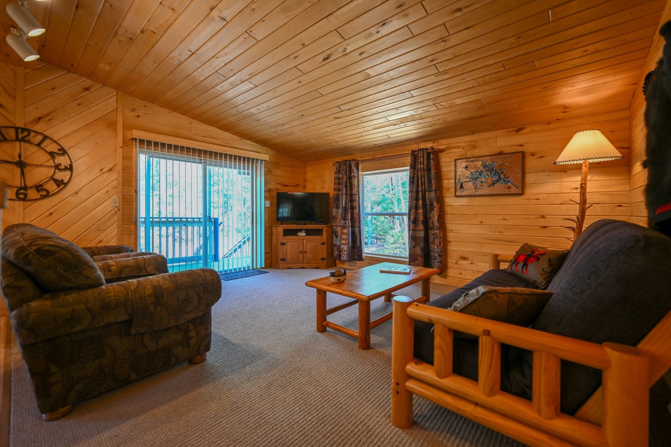 Unwind in your cozy log cabin living room with plush seating, warm wood accents, and peaceful forest views through large windows.