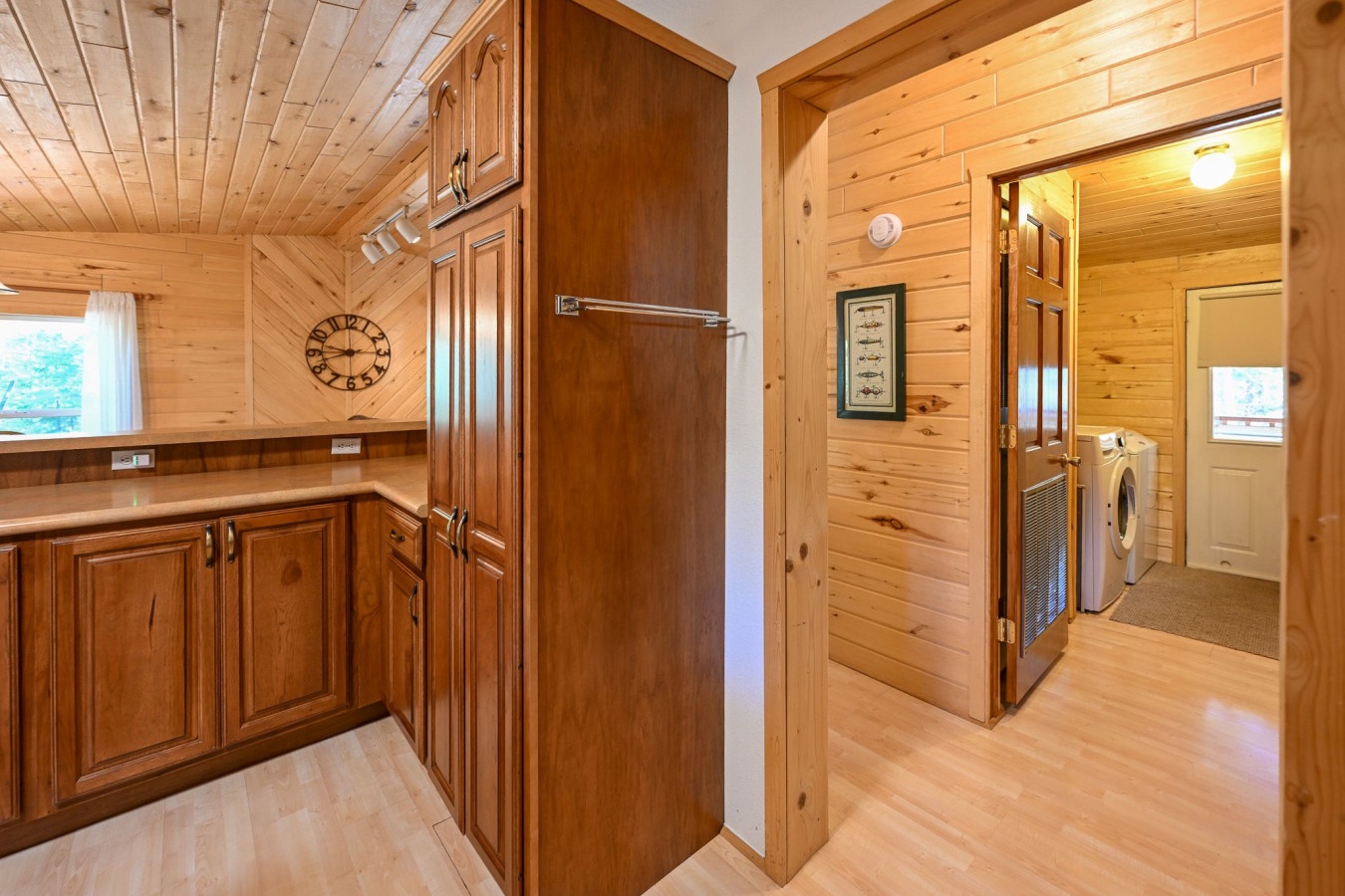 Your cozy cabin kitchen flows seamlessly into the laundry room, where warm wood and modern appliances create the perfect home-away-from-home.