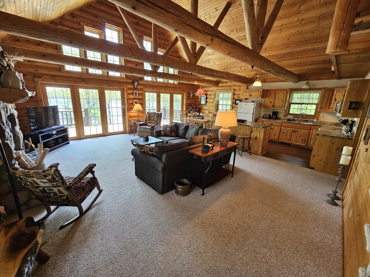 Unwind in your rustic cabin retreat where exposed beams frame cozy seating and a fully-equipped kitchen awaits your culinary adventures.