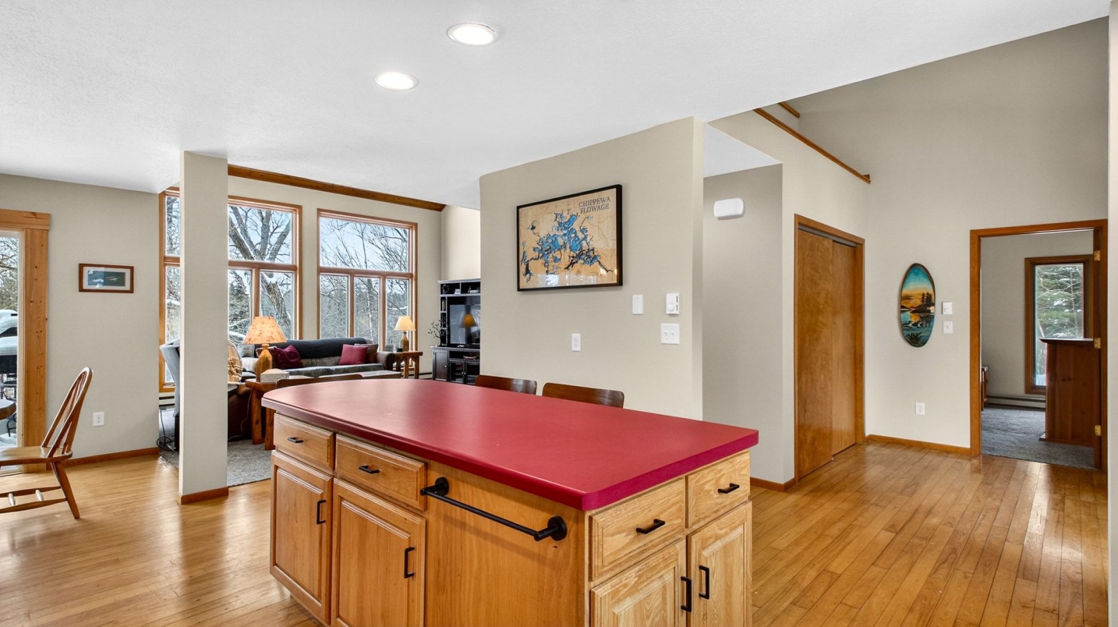 Your spacious kitchen island with rich red countertop creates perfect gathering space, while warm wood floors flow throughout your open-concept home.