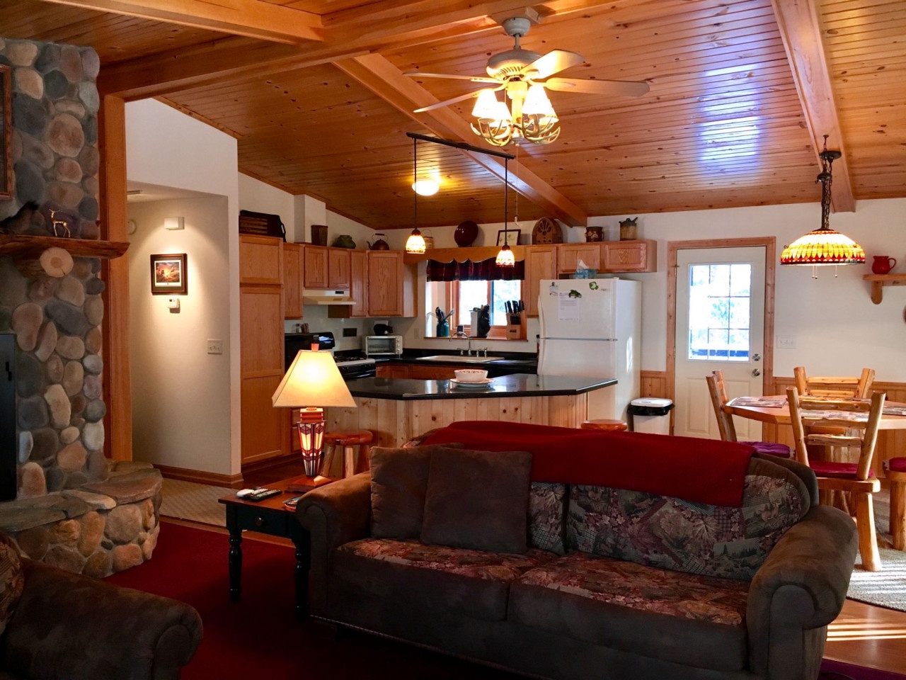 Sink into this cozy living area where warm wood ceilings and stone fireplace create your perfect mountain retreat atmosphere.