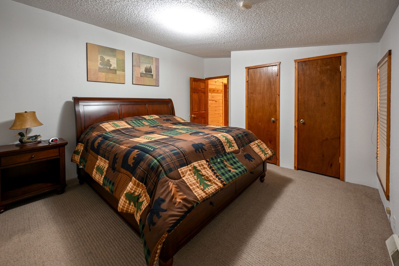 Unwind in your cozy bedroom featuring rich wood accents and a plaid quilt that invites restful mountain dreams.