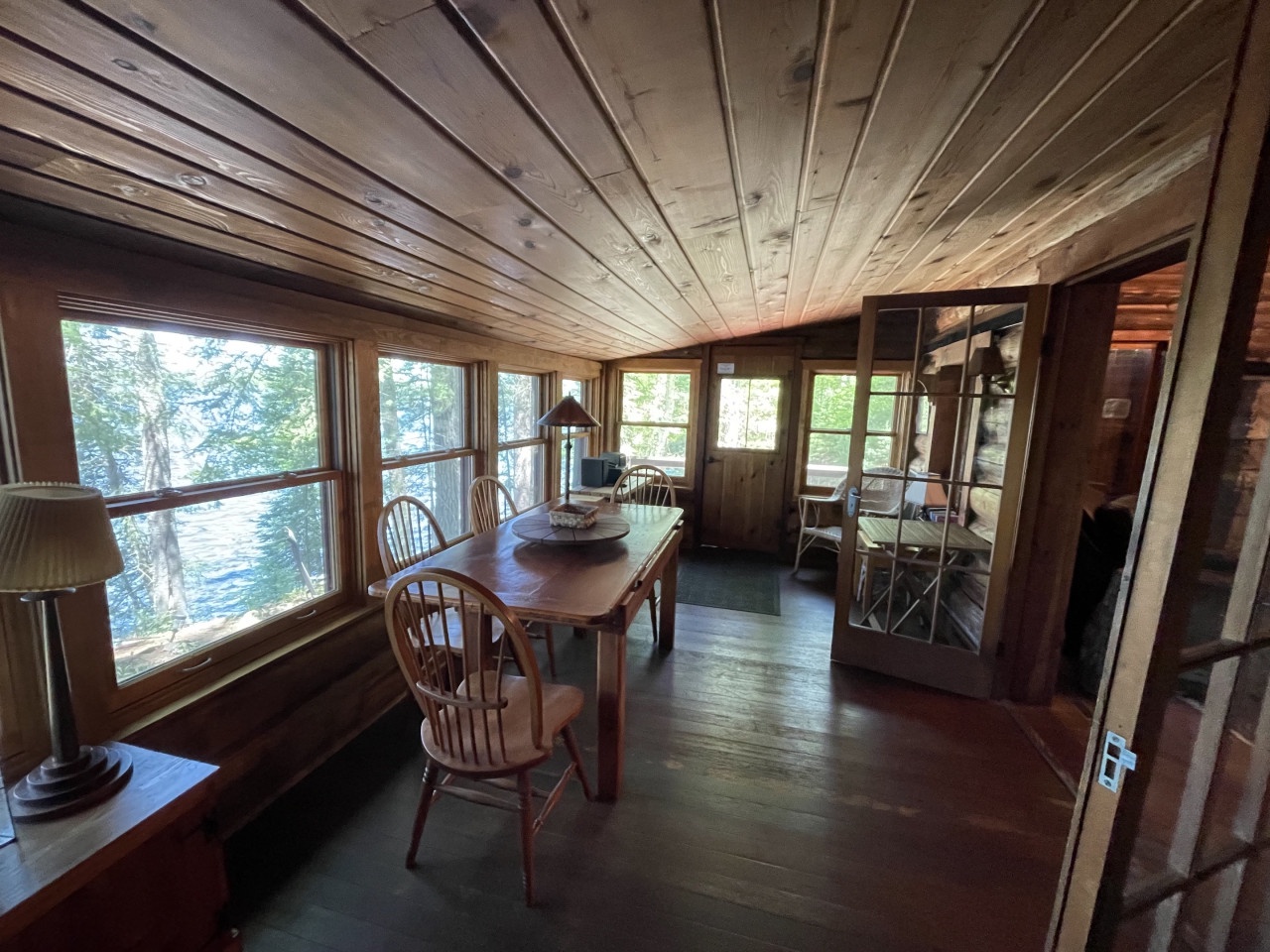 Gather around your rustic dining table with woodland views streaming through every window, creating the perfect lakeside retreat atmosphere.