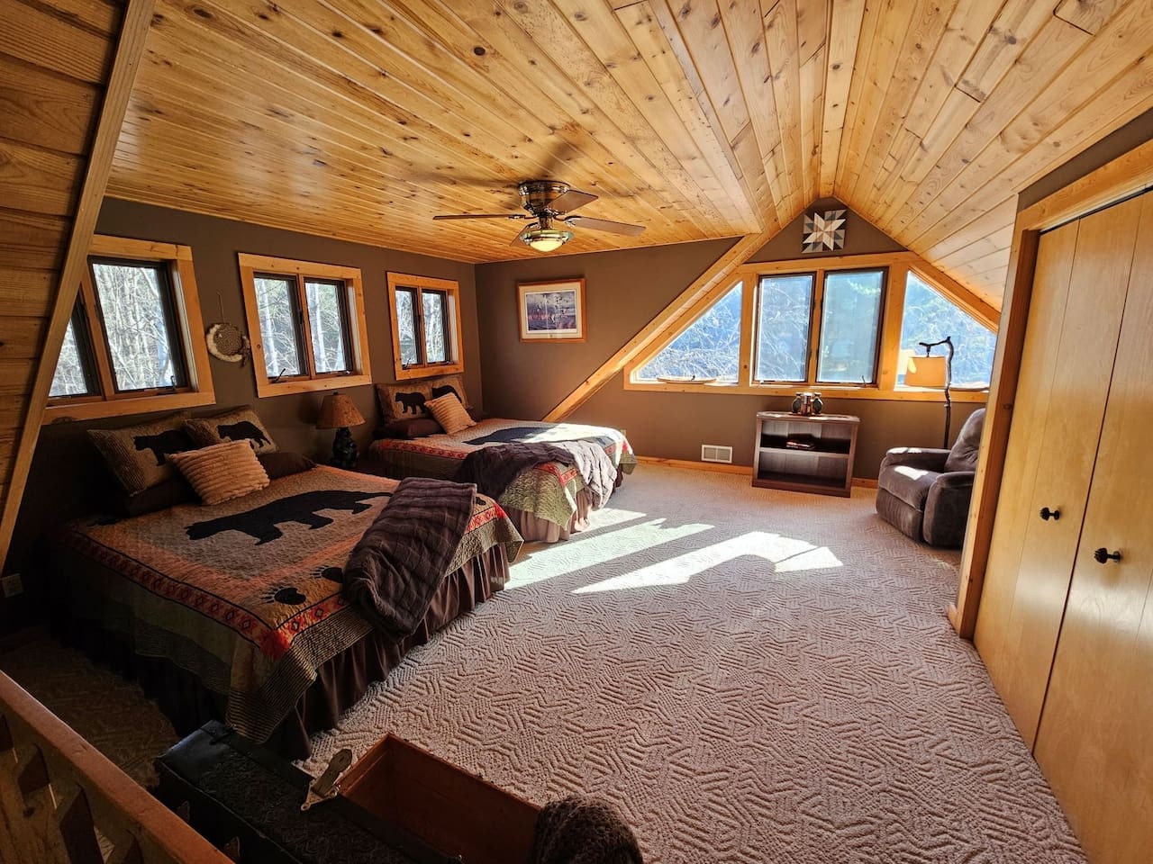 Drift off in this cozy loft bedroom where rustic wood beams frame mountain views through charming windows, creating your perfect alpine retreat.