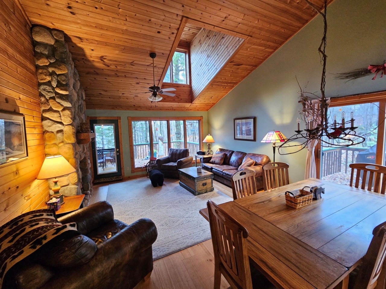Cozy up in this rustic cabin where stone fireplace warmth meets forest views through large windows.