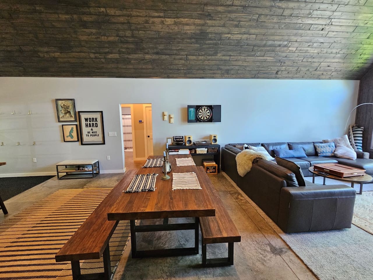 Unwind in your spacious living area with striking wood ceiling, cozy sectional seating, and entertainment center for ultimate relaxation.