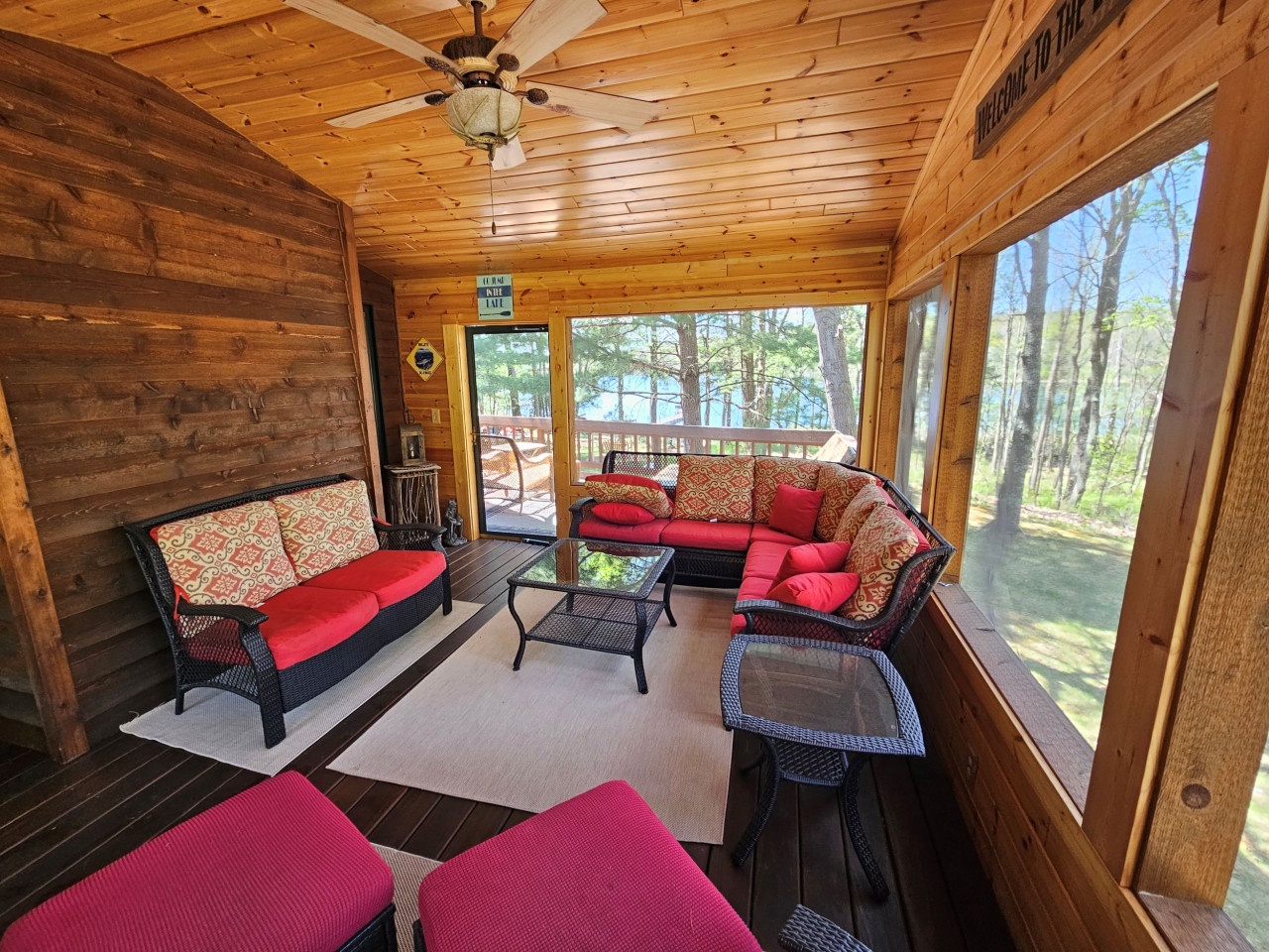Unwind in this cozy screened porch with comfortable seating and stunning lake views through towering trees.