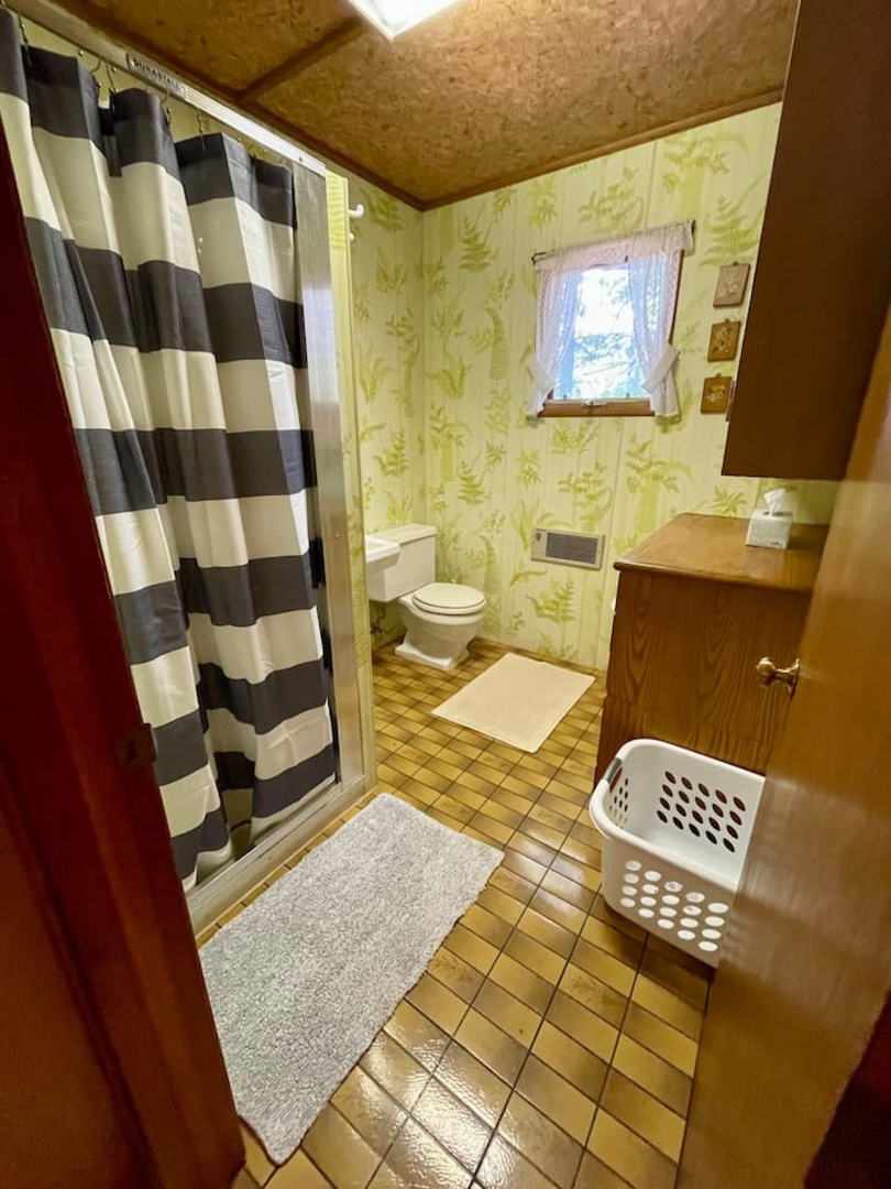 Your private bathroom features charming vintage wallpaper, a convenient shower-tub combo, and thoughtful touches like fresh towels and a laundry basket.