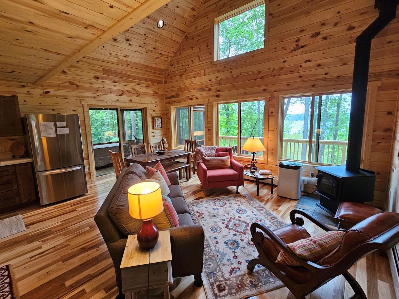 Relax in this cozy cabin living room where warm wood surrounds you and forest views fill every window. Gather around the fireplace with loved ones.