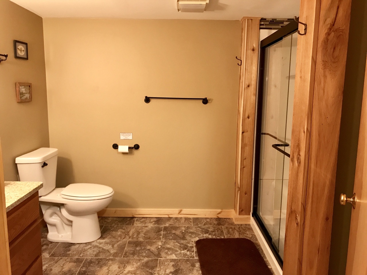 Your private bathroom features a spacious walk-in shower and warm wood accents that create a cozy, cabin-like atmosphere for your stay.