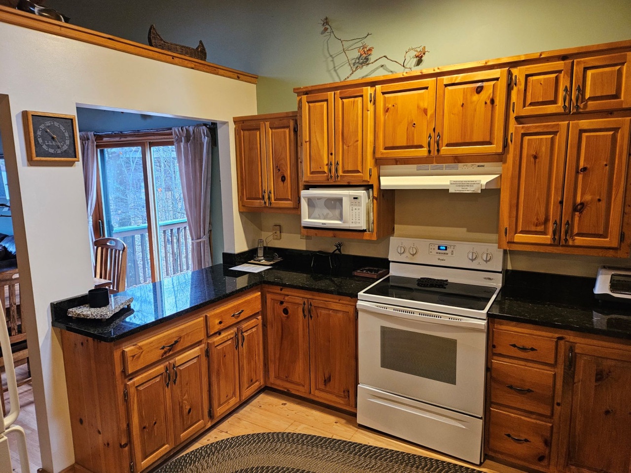 Your fully equipped kitchen features warm knotty pine cabinets, granite countertops, and modern appliances for preparing family meals.