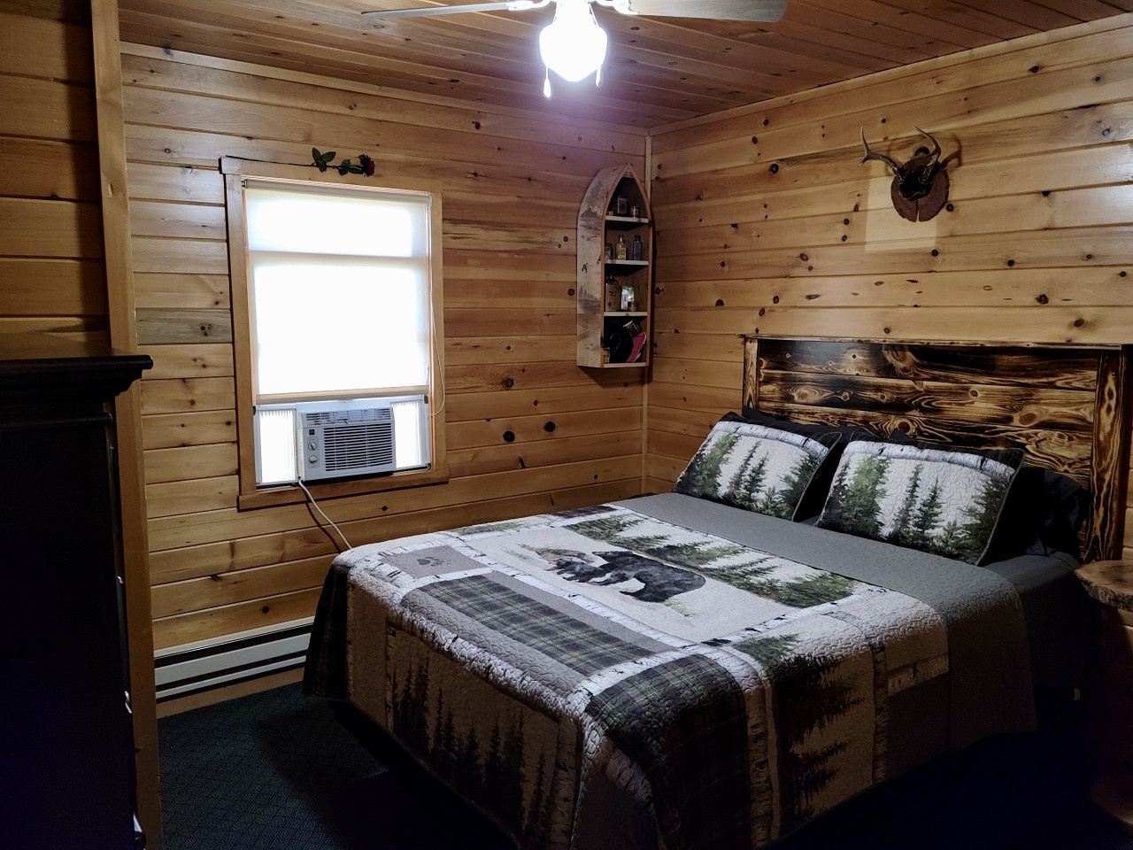 Your cozy cabin bedroom features warm wood walls, rustic charm, and nature-themed bedding that'll cradle you in wilderness comfort.