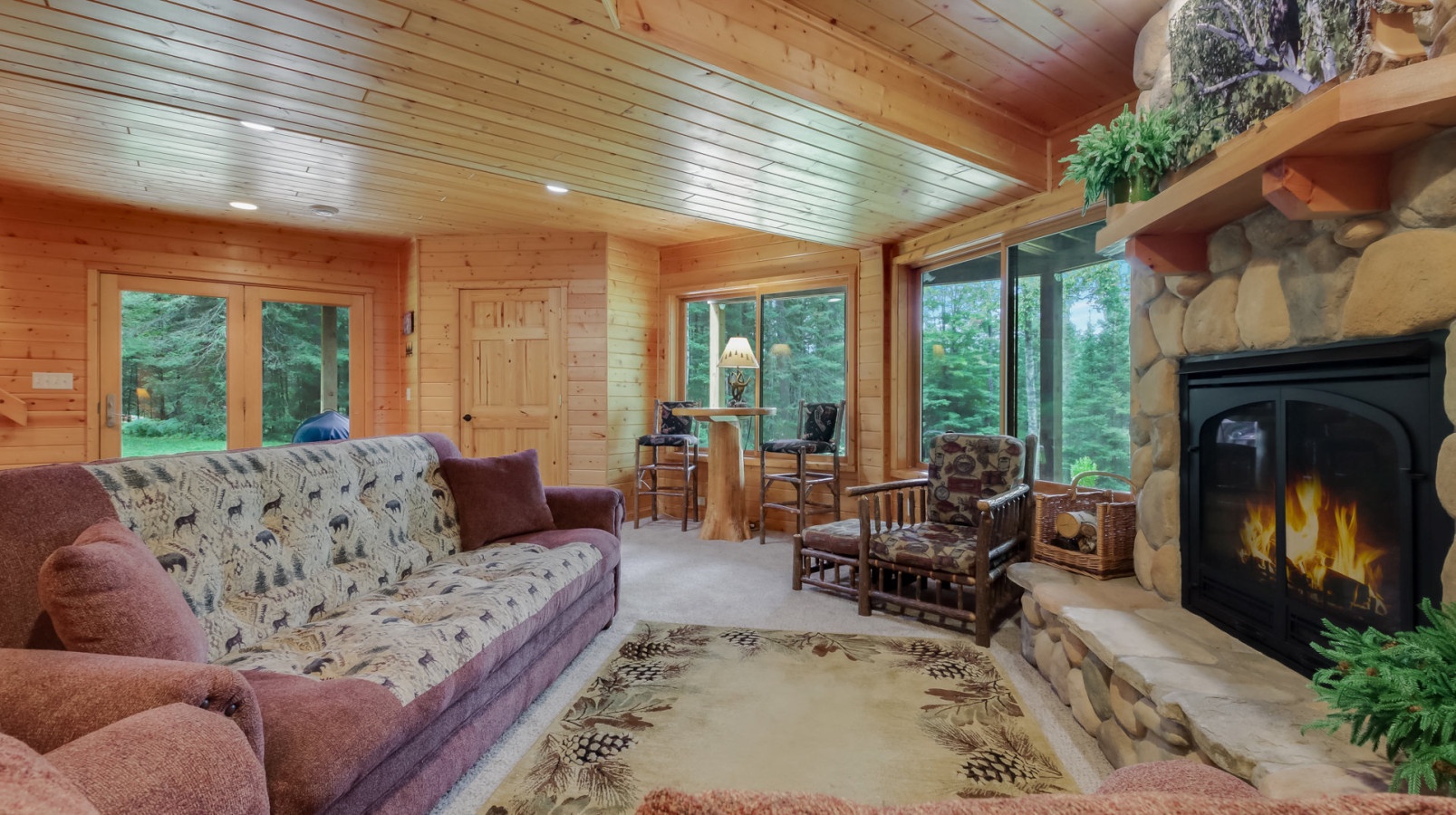 Cozy up by your crackling fireplace in this warm cabin living room, where wood beams and forest views create your perfect retreat.