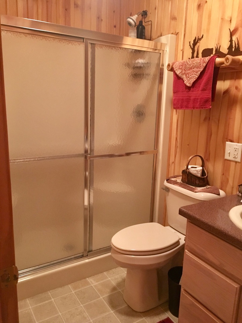 Your private bathroom features a spacious glass shower, warm wood paneling, and thoughtful touches like fresh towels to make you feel at home.