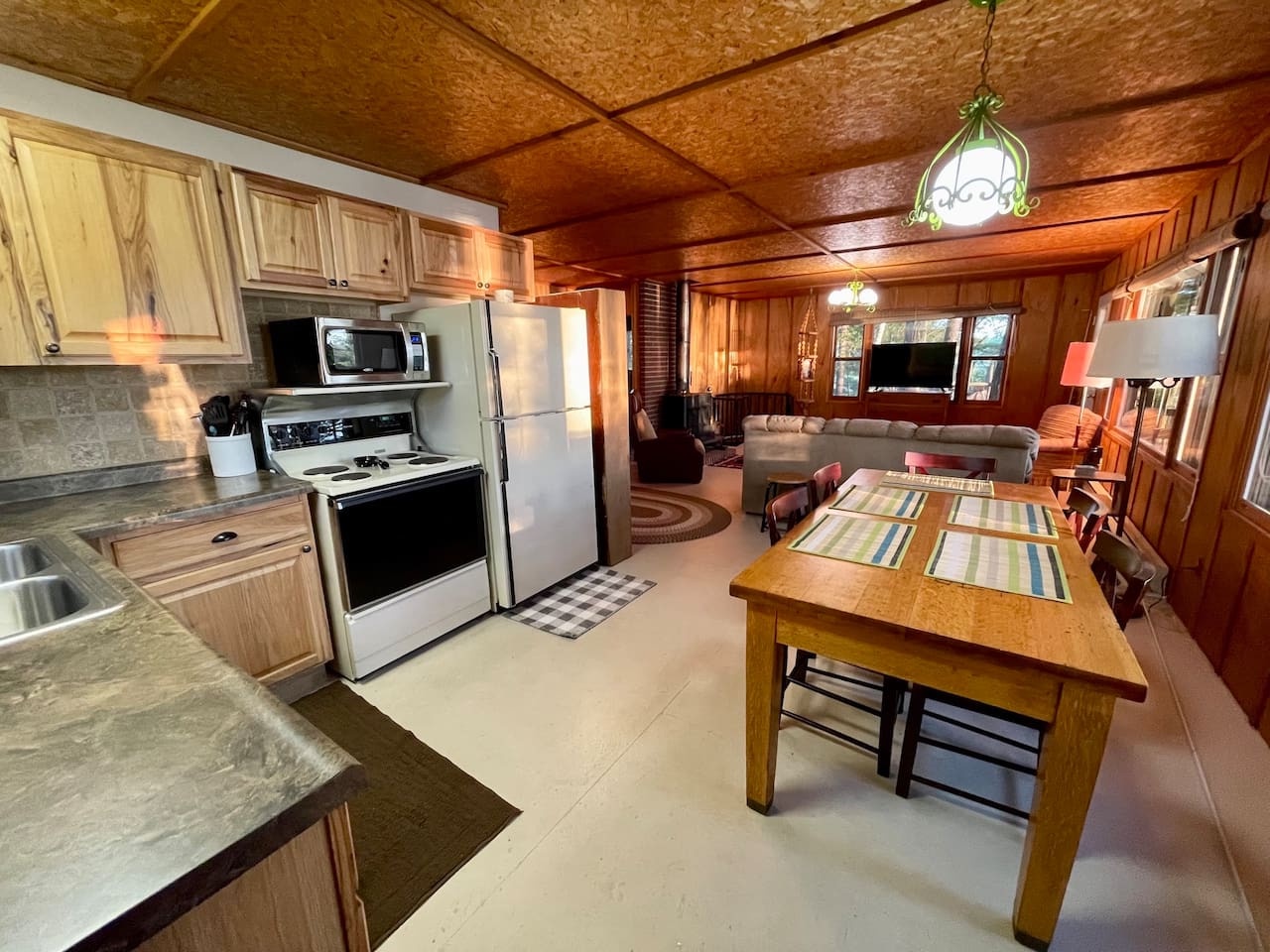 Your rustic cabin retreat features warm wood paneling, a fully equipped kitchen, and cozy dining area perfect for home-cooked meals.