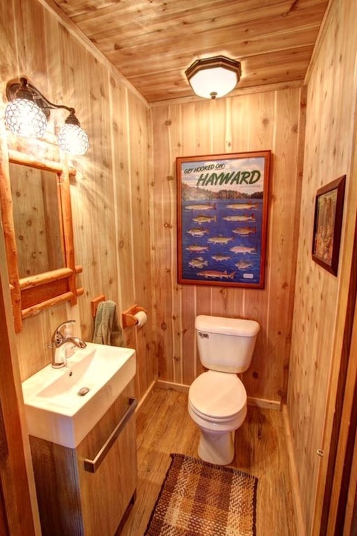 Step into your cozy cabin bathroom, where warm wood walls and charming nautical touches create a rustic retreat.