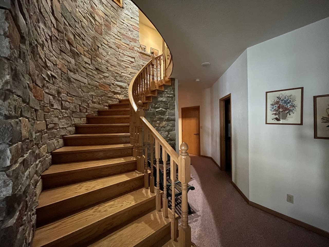 Admire the stunning curved wooden staircase with exposed stone wall as you make your way to your comfortable accommodations above.