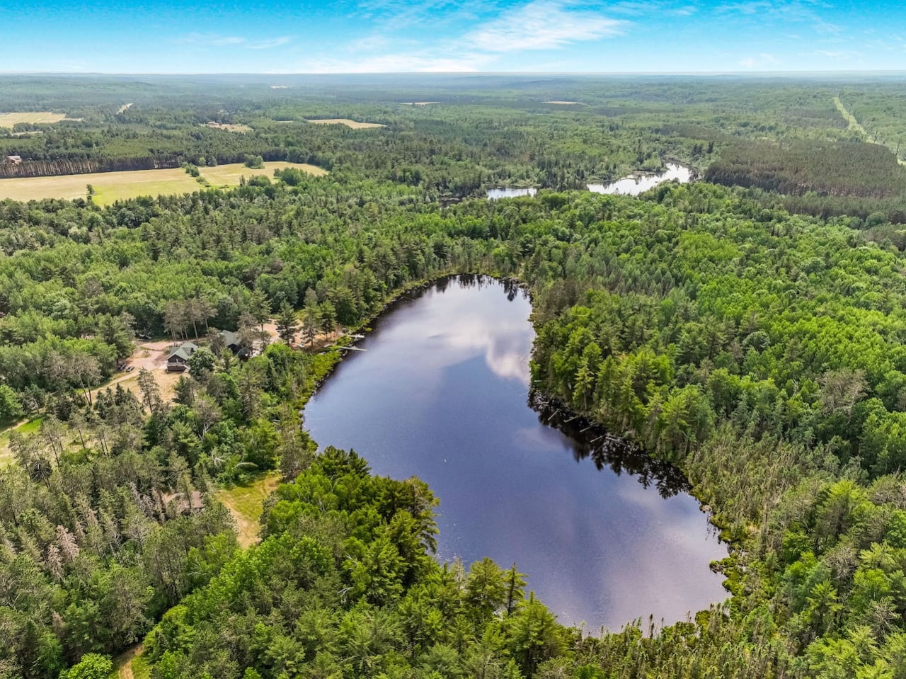 Pristine lake surrounded by dense forest creates a peaceful natural setting for the property area.