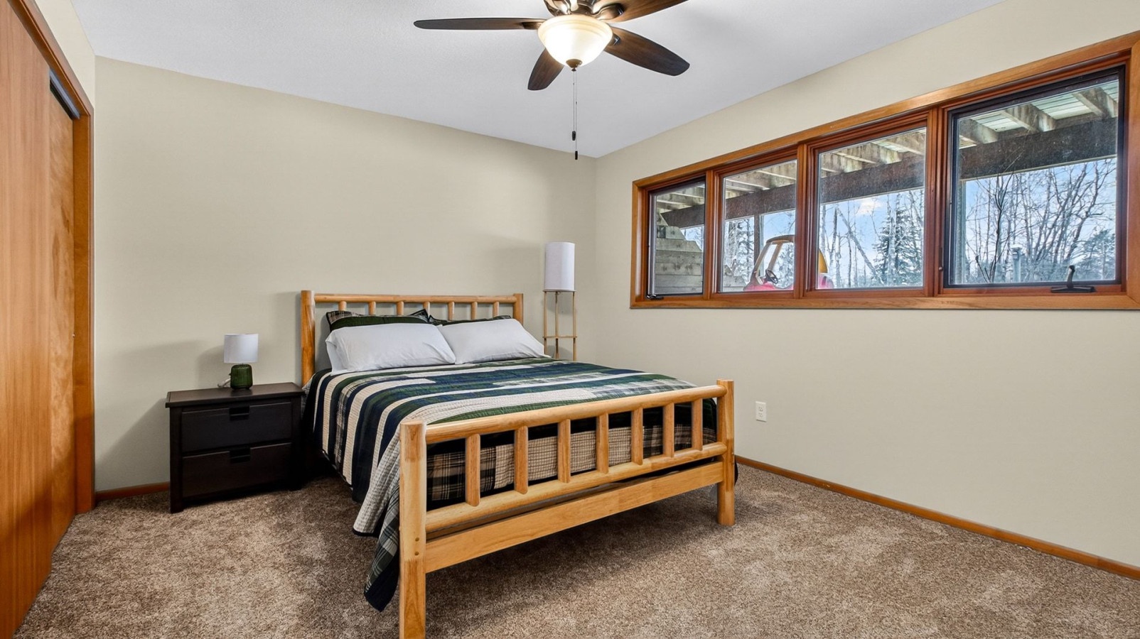 Rest peacefully in your cozy bedroom featuring a comfortable bed, bedside lamps, and windows overlooking serene winter scenery.