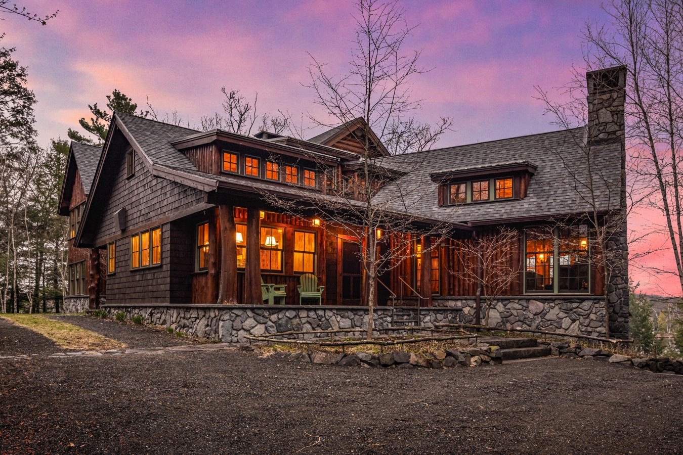 Stunning rustic lodge with warm lighting nestled among towering trees beneath a painted sunset sky.