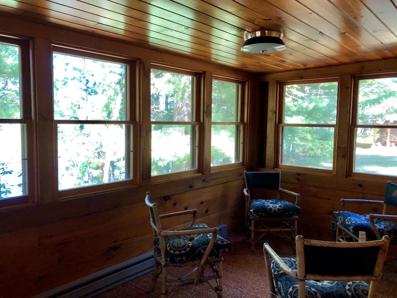 Cozy sunroom where you can unwind in comfortable seating while enjoying peaceful garden views through wraparound windows.