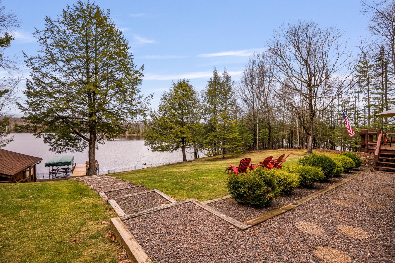 Peaceful lakefront setting with Adirondack chairs perfectly positioned for enjoying serene water views and natural surroundings.